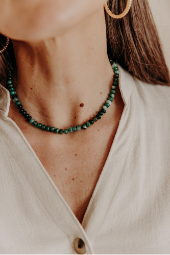Femme qui porte un collier en perles vertes.