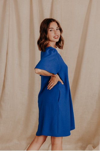 Femme de profil qui porte une robe unie bleue festonnée