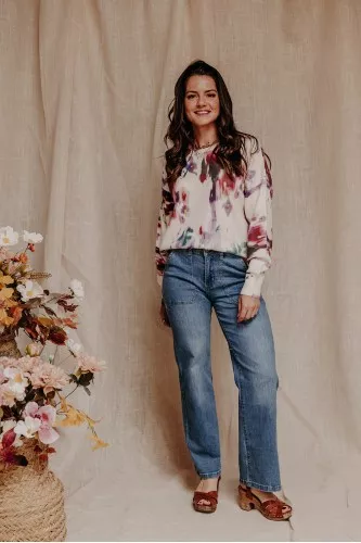 femme debout qui porte un pull à fleurs et un jean large