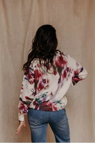 femme de dos qui porte un pull imprimé à fleurs et un jean