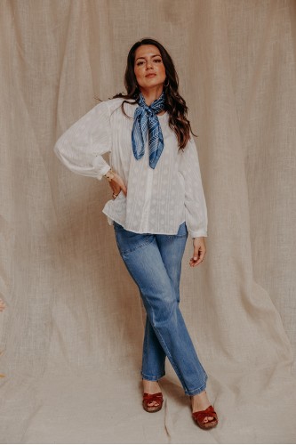 femme debout qui porte un carré de soie, une chemise blanche et un jean