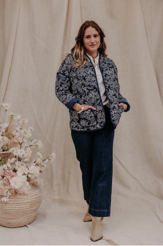 Femme debout qui porte une veste matelassée et un jean brut.