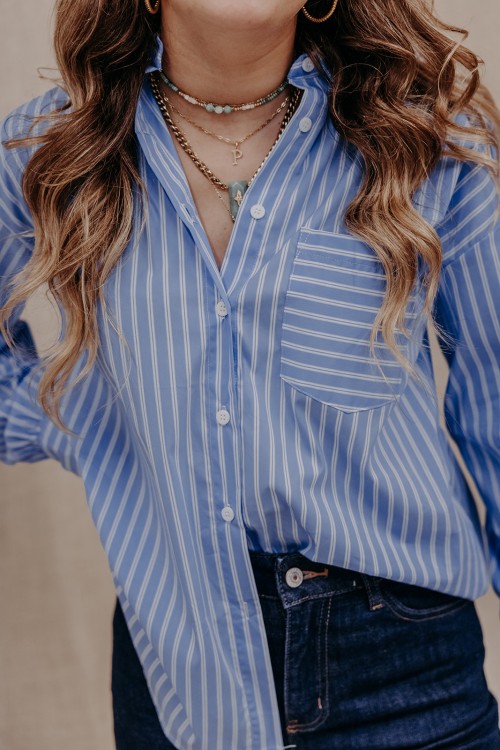 Femme qui porte une chemise rayée bleue.