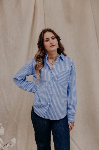 Femme debout qui porte une chemise rayée bleue et un jean.