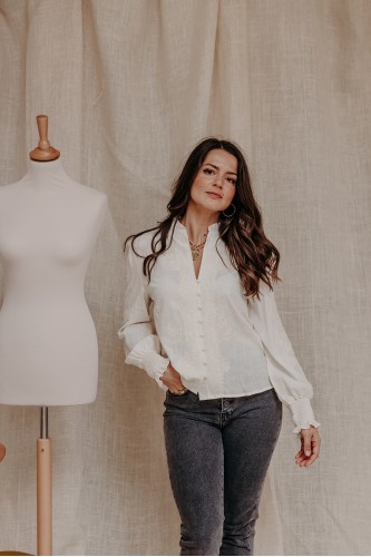 Femme avec une blouse brodée écrue.