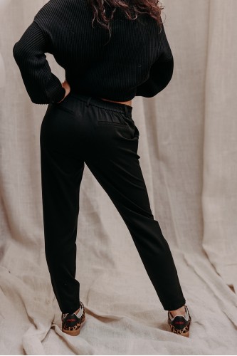 Femme de dos avec un pantalon noir.