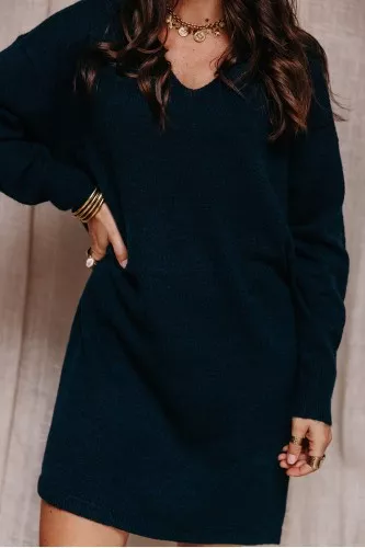 Femme qui porte une robe pull et des bottes noir.