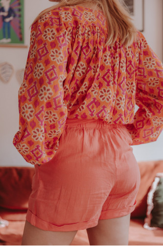 Femme de dos qui porte un short en lin orange