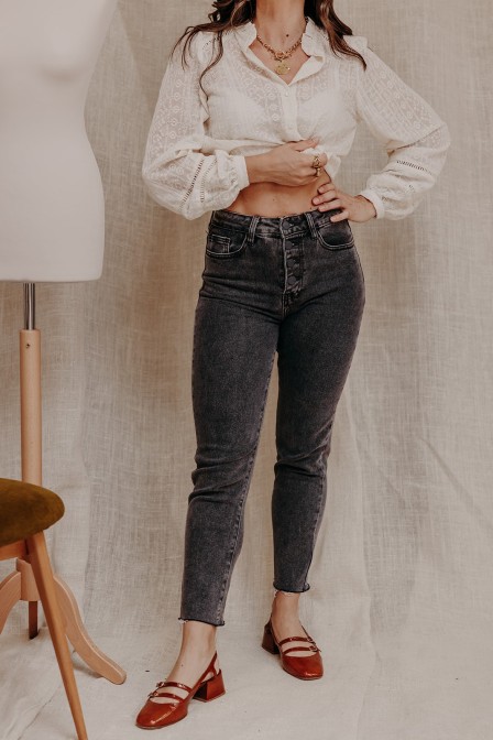 Femme qui porte un jean gris et une chemise écru.