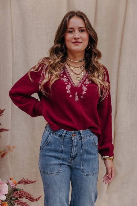 Blouse de couleur bordeaux porté par une femme.