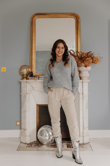 Femme debout qui porte un pantalon slouchy écru.