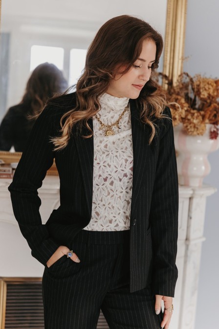 Femme qui porte un blazer noir à fines rayures.