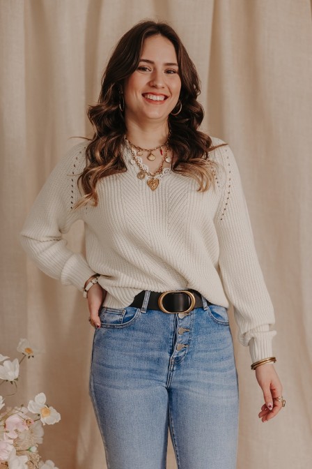 Femme portant un pull beige à dentelle.