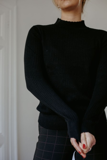 Femme portant un pull noir.